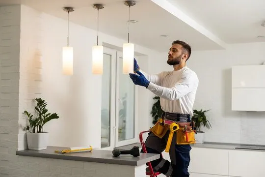 Electrician installing pendant lighting in a new kitchen